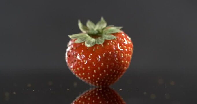 One strawberry rotating around its axis on black background in slow motion
