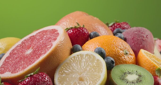 assorted fresh colorful fruits and berries rotating in a vibrant composition. Juicy peach, orange, strawberries, blueberries, kiwi, and grapes