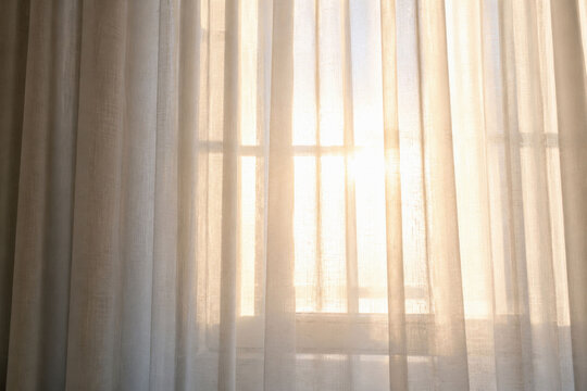 Sunlight Through Sheer Curtains. Bright golden morning rays penetrate window drapes, symbolizing hope and a peaceful new start to the day with warm serene energy.