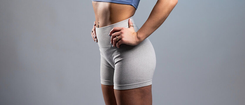 Fit woman in gray textured workout shorts posing with hands on hips