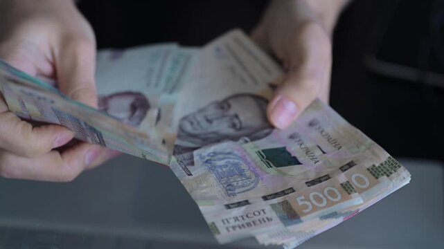 Close-up hands counting Ukrainian hryvnia banknotes