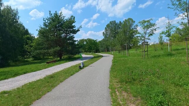 Paved path winding through green park with wooden swing structure