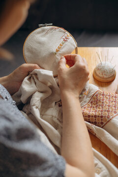 Woman embroidering traditional ukrainian cross stitch pattern