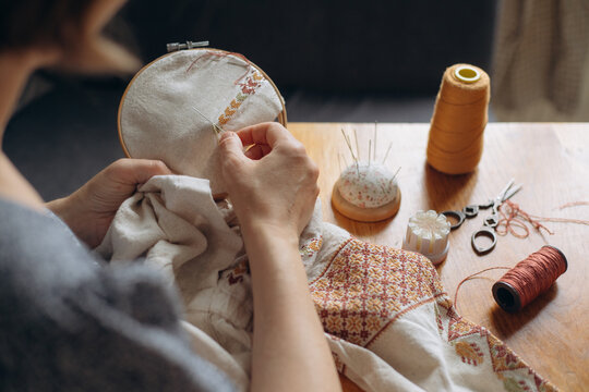 Woman's hands embroidering traditional ukrainian cross stitch pattern