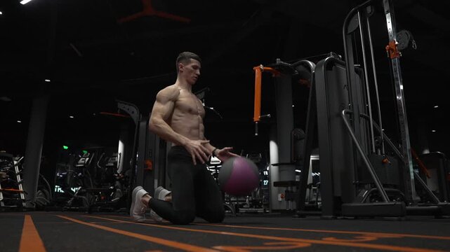 Fitness workout of sportsman with ball in gym. Sportsman do workout in fitness gym. Muscular man throw fitness ball on gym floor. Fit man ball workout in fitness gym. Ball strike