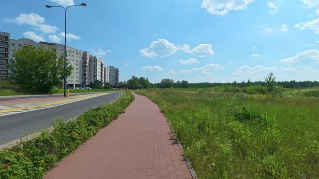 Bicycle path running past apartment blocks in suburban meadow