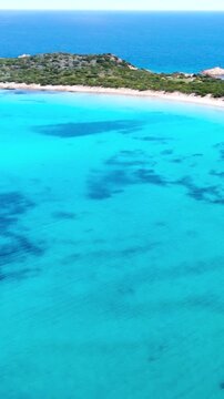 Vertical drone aerial view of crystal clear turquoise sea and coast at Capo Coda Cavallo, San Teodoro, Sardinia, Italy. Scenic Mediterranean coastline summer footage.