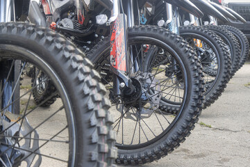 Fototapeta premium Row of Off-Road Enduro Motorcycles Front Wheels with Aggressive Knobby Tires and Disc Brakes