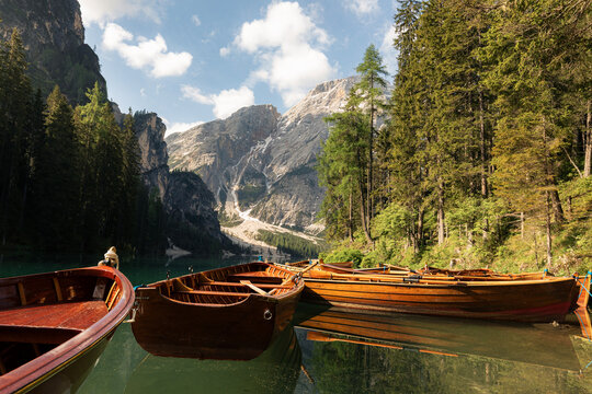Traditional rowing wooden boats on calm water of Lago di Braies lake in mountain landscape of Dolomites Alps Italy. Outdoor recreation, eco tourism, summer vacation and alpine nature concept.