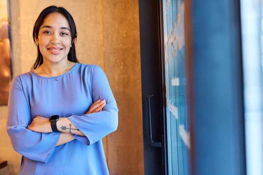 Portrait of a young  businesswoman woman posing in front of a wall in the office