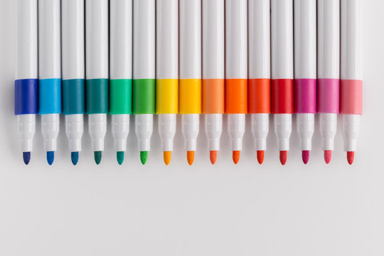 Top view of colorful felt tip pens arranged in a row gradient on white background
