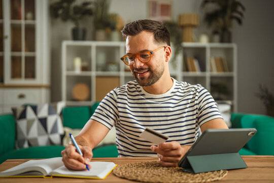 Man shopping online using tablet and credit card at home