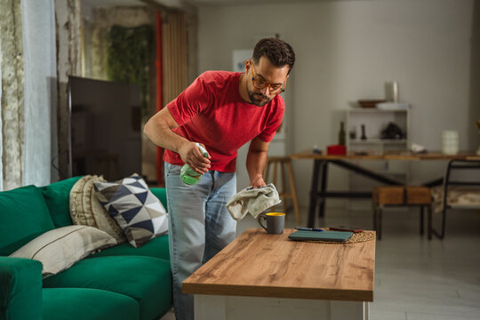 Man cleaning living room coffee table, doing housework