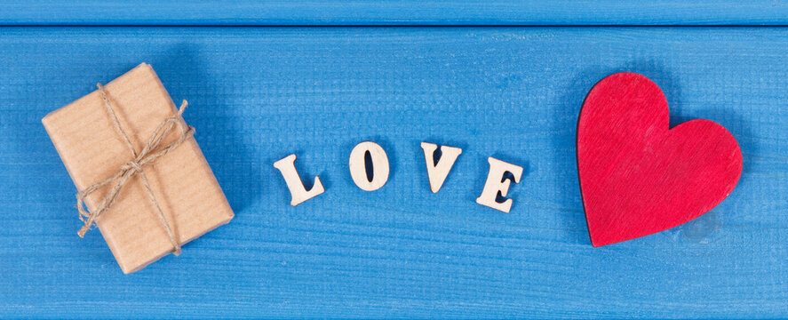 Gift with ribbon, red heart and word love as surprise for Valentines Day or other celebration