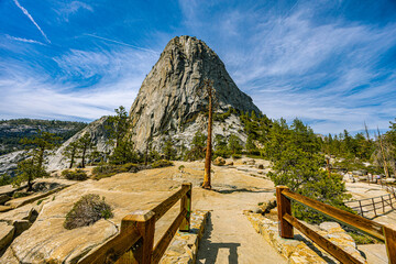 Liberty Cap's granite dome rises above a scenic overlook with wooden railings and a lone pine tree in Yosemite National Park.  © ZL Visuals