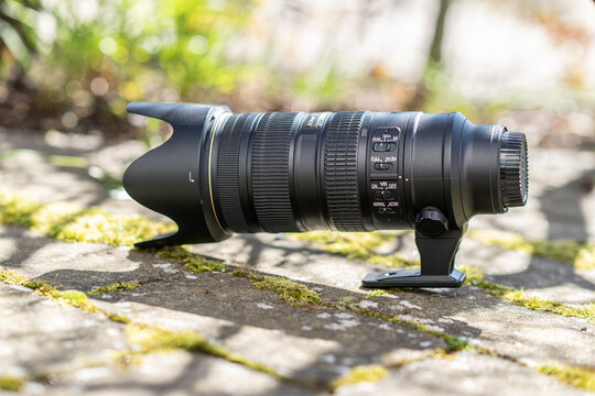 Gothenburg, Sweden - April 21 2024: professional telephoto zoom lens with tripod collar resting on stone ground.