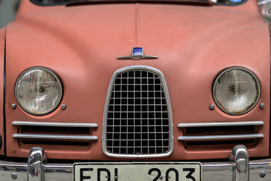 Gothenburg, Sweden - May 30 2026: Front grille and headlamps of matte pink classic Saab automobile.