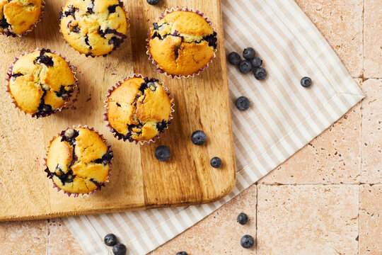 Homemade blueberry muffins on wooden board with fresh berries