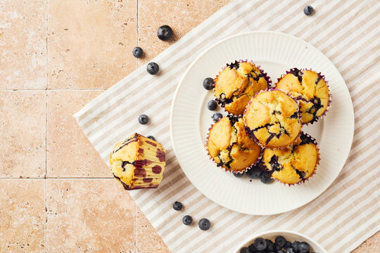Freshly baked blueberry muffins on plate with striped napkin