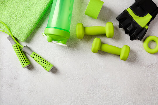 Top view green fitness accessories on concrete background