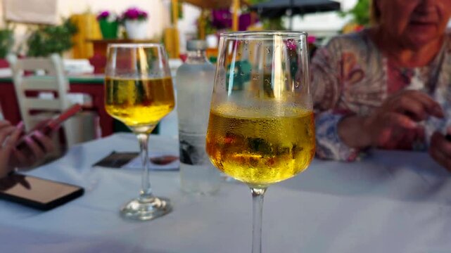 Cold White Wine Glasses Served On Outdoor Restaurant Table. Chilled Beverage Condensation. Refreshing Drink