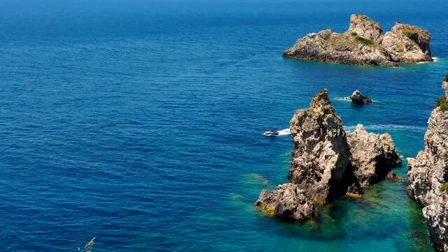 Rocky Cliffs In Deep Blue Sea Water. Boat Sailing Past Island. Coastline Mediterranean 