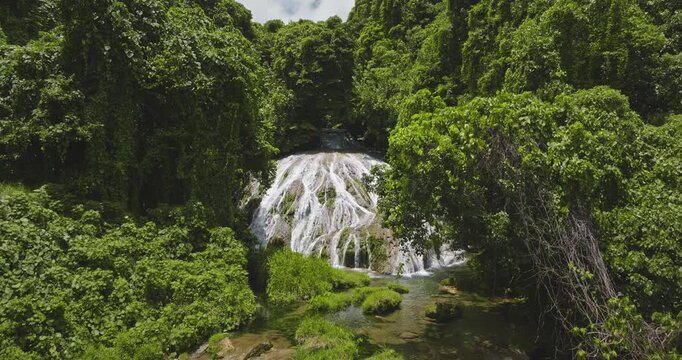 Waterfall with slow motion water cascading over vibrant green rocks and jungle forest foliage, natural beauty of the untouched Vanuatu environment, Port Villa, Efate Island. Drone footage aerial shot