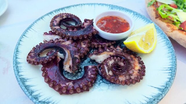 Grilled Octopus Tentacles Served With Red Sauce And Lemon Wedge. Mediterranean Seafood Dish. Gourmet Meal