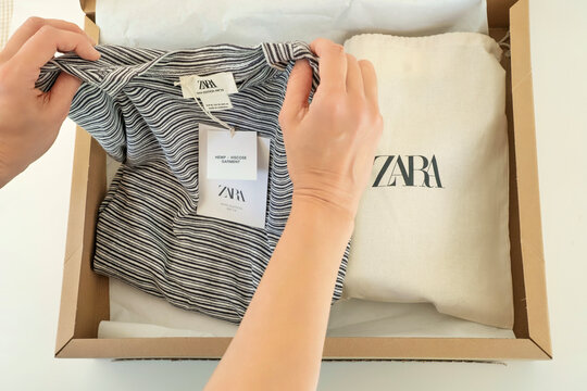 Alicante, Spain - January 30, 2025: Online shopping in Zara clothing store. Woman hands open cardboard box with new clothes and shoes. Zara is global fashion retailer of Inditex group
