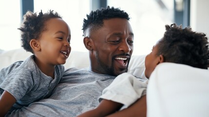 Obraz premium Father happy and laughing with his two young sons on a couch, enjoying playtime and having fun at home, celebrating family bonding and paternal love