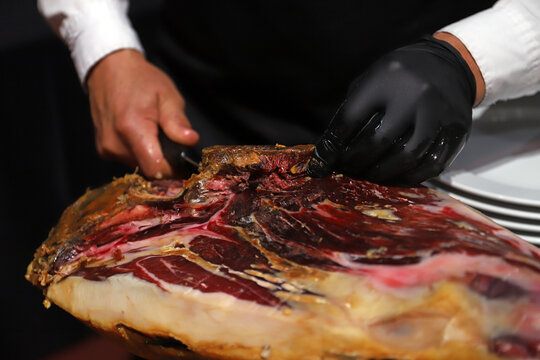 maestro jamonero preparando un jam&oacute;n ib&eacute;rico y quit&aacute;ndole la costra exterior