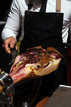 profesional de la charcuter&iacute;a quitando la costra de un jam&oacute;n ib&eacute;rico