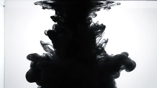 Black ink dissolving and spreading through clear water with a soft and dreamy effect for abstract artistic visuals