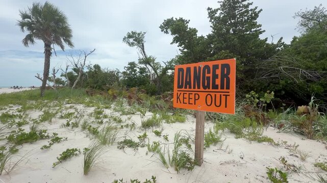 Orange "Danger Keep Out" warning sign at Sanibel Lighthouse Beach, Florida. The sign marks a restricted area near the shoreline, emphasizing public safety in a popular coastal destination.