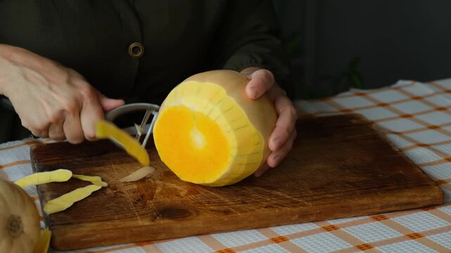Person peeling pumpkin. Preparing autumn food. Cooking pumpkin soup or cake.