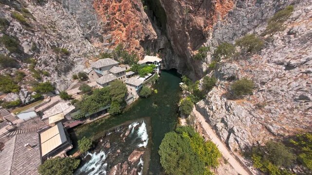 Aerial view of Blagaj Tekke dervish house and Buna river spring under steep rock cliff in Bosnia