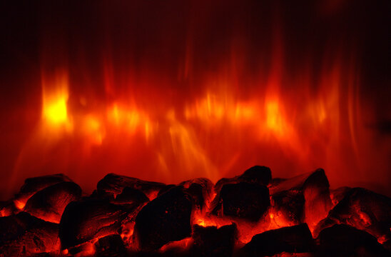 Glowing embers with flickering flames producing intense heat, warmth, and energy, creating an abstract fire background