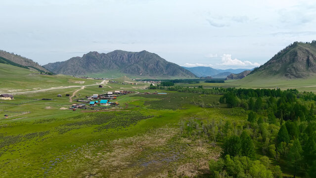 Breathtaking high-angle panoramic aerial view of the expansive green Elo valley surrounded by dramatic mountain ridges and deep forests in Altai.