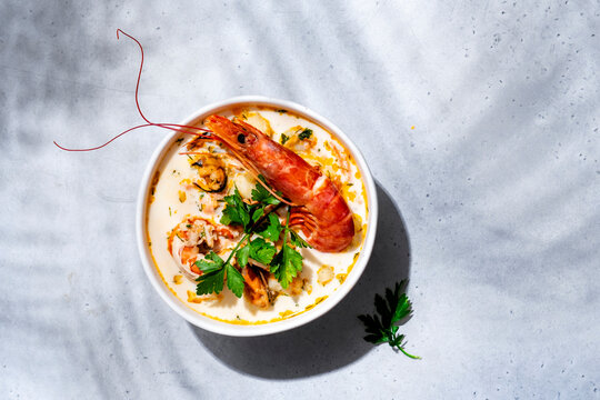 Seafood chowder soup with langoustine, shrimp, mussels in bowl on light background. Gourmet Mediterranean restaurant dining banner background, luxury seafood delicacy concept.