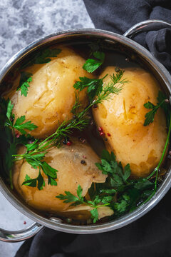 Boiled potatoes in skin with green herbs in metal pot macro photo