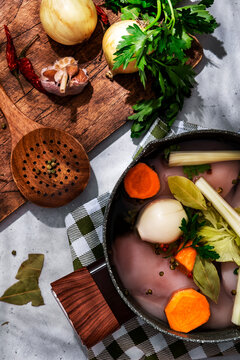 Homemade chicken broth raw ingredients. Fresh poultry, garlic, chili pepper, and aromatic spices background.