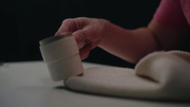 Person using electric fabric shaver to remove lint and pilling from winter hat, restoring smooth, fresh looking textile surface for cleaner, renewed garments, close-up. Shooting in slow motion.