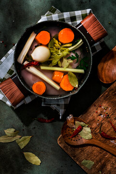 Fresh ingredients for chicken broth with a wooden spoon and spices