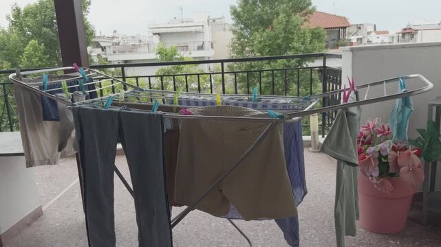 Wet Clothes Drying On Metal Folding Laundry Rack Stand On Apartment Balcony. Household Chores. Domestic Routine Life City