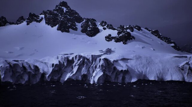 Close view of glacier ice cliffs with deep crevasses, windsculpted seracs, broken surfaces, dark sea foreground and stark geological detail