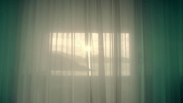 Sunlight streaming through sheer white curtains covering a window, creating a soft, ethereal glow in a room.