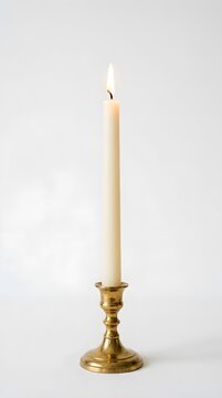 A single white candle burning with a bright flame in a brass candlestick holder isolated on a plain light background perfect for spiritual or cozy