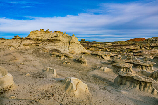 Wide landscape view of a vast hoodoo field featuring strange eroded rock shapes and clay mounds under a dynamic blue sky.