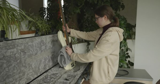 Musician Girl Cleans Bass Guitar Wiping Dust. 4K 10-bit