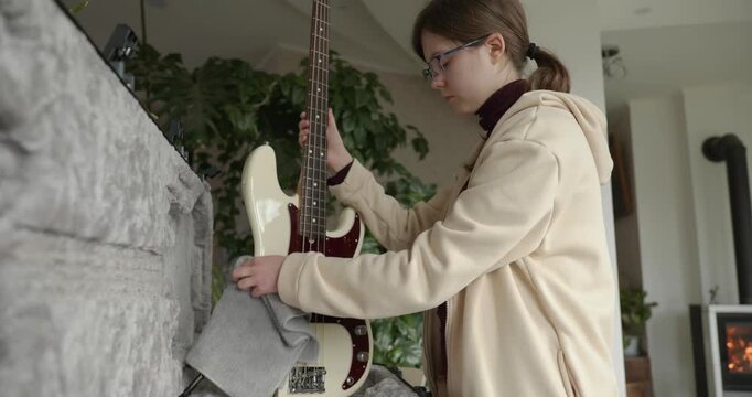 Musician Girl Cleans Bass Guitar Wiping Dust. 4K 10-bit